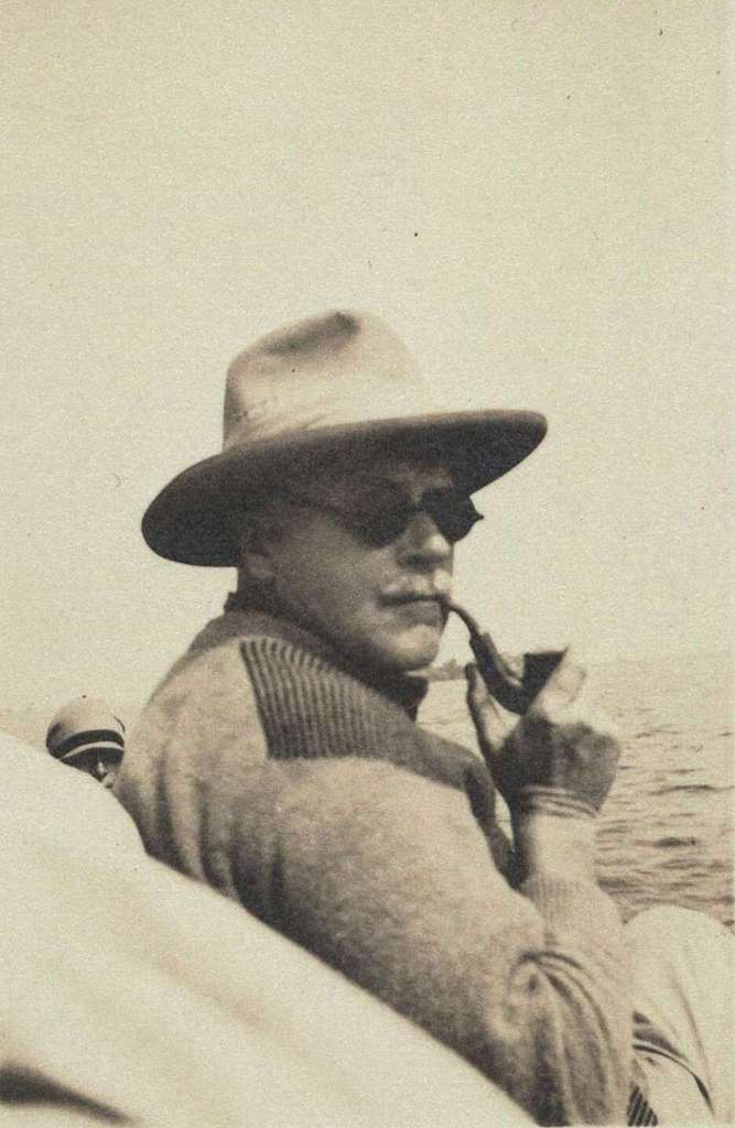 Carl Jung in a hat and sunglasses, smoking a pipe on a boat